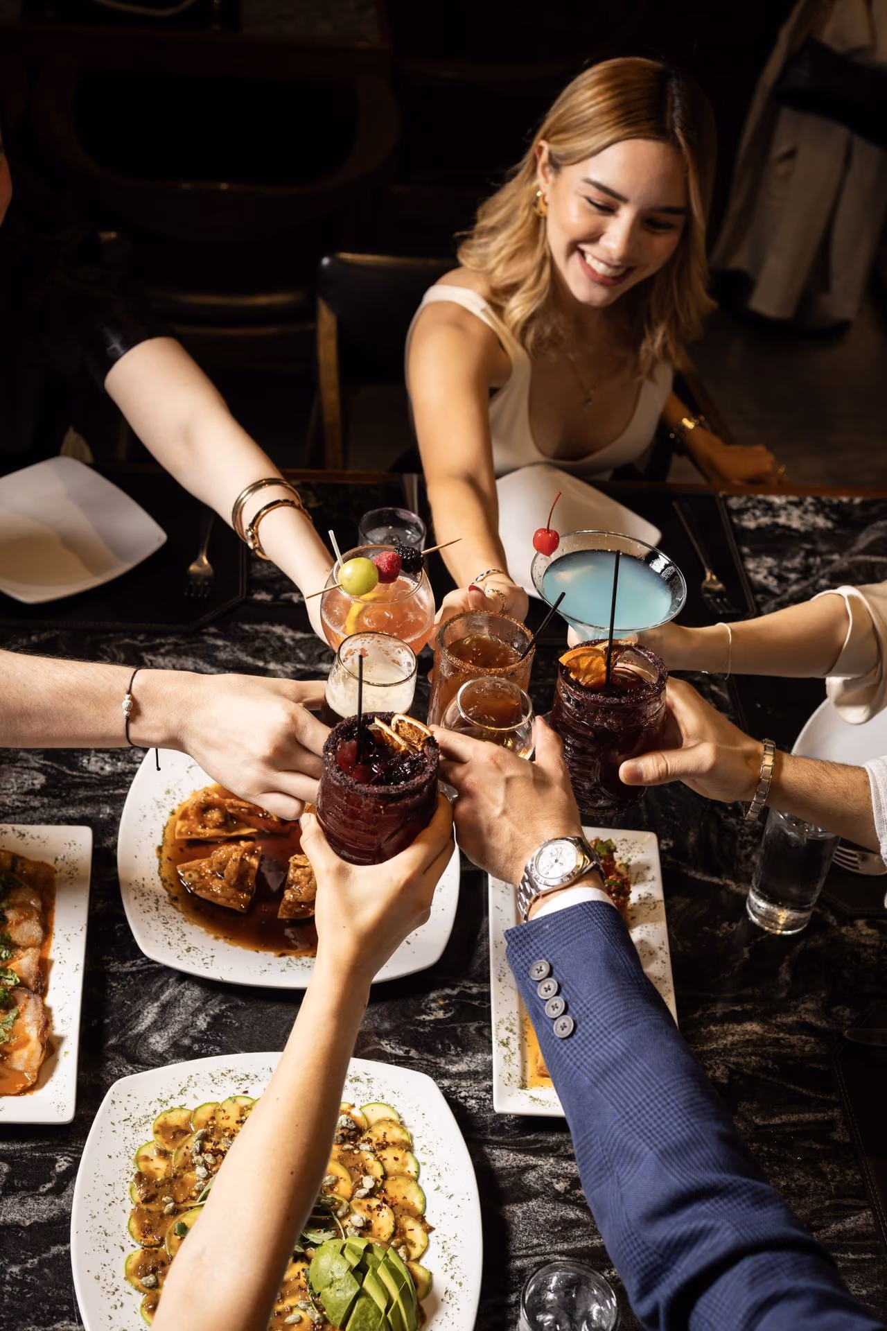 Brindis de amigos sobre una mesa con varios platillos