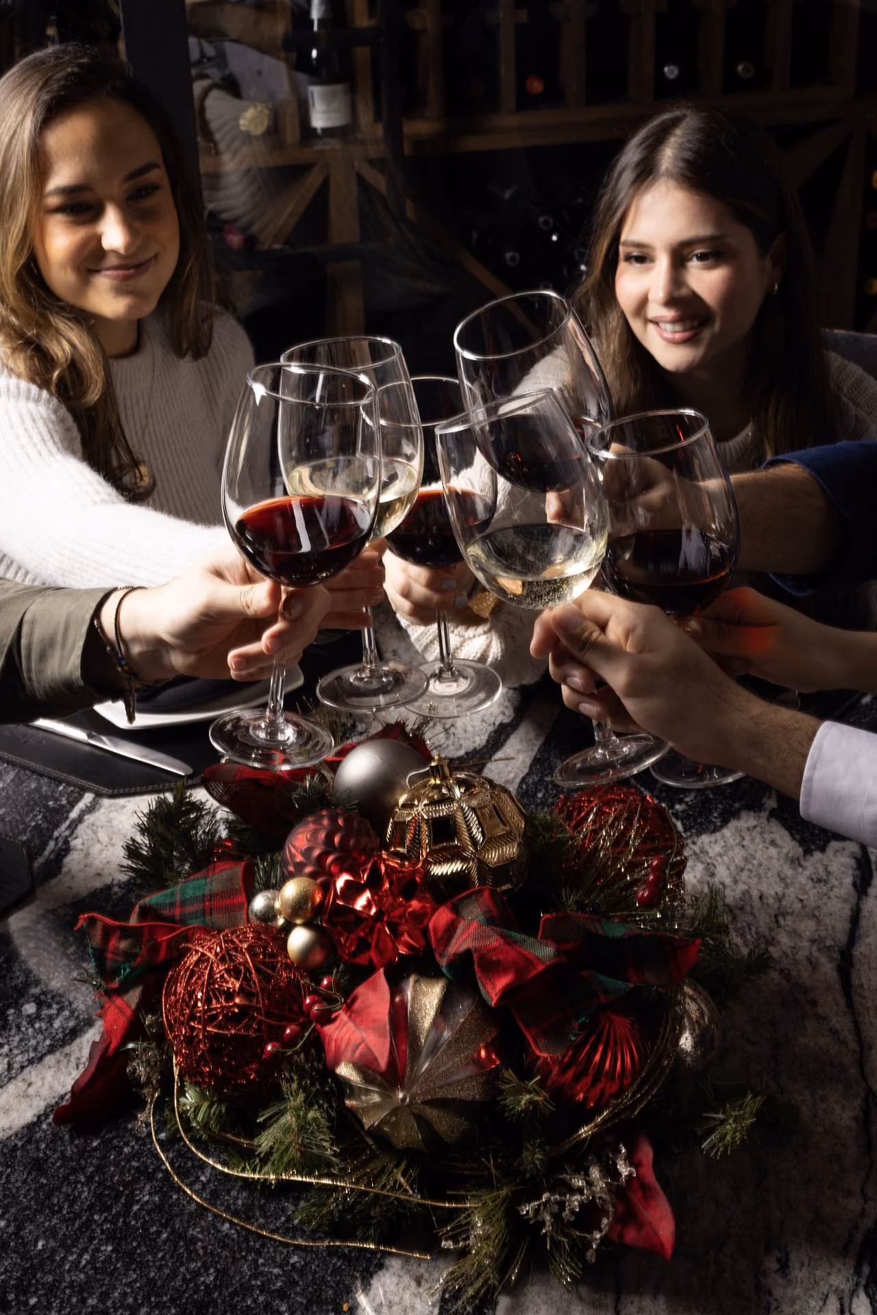 Amigas brindando con vino sobre un centro de mesa navideño