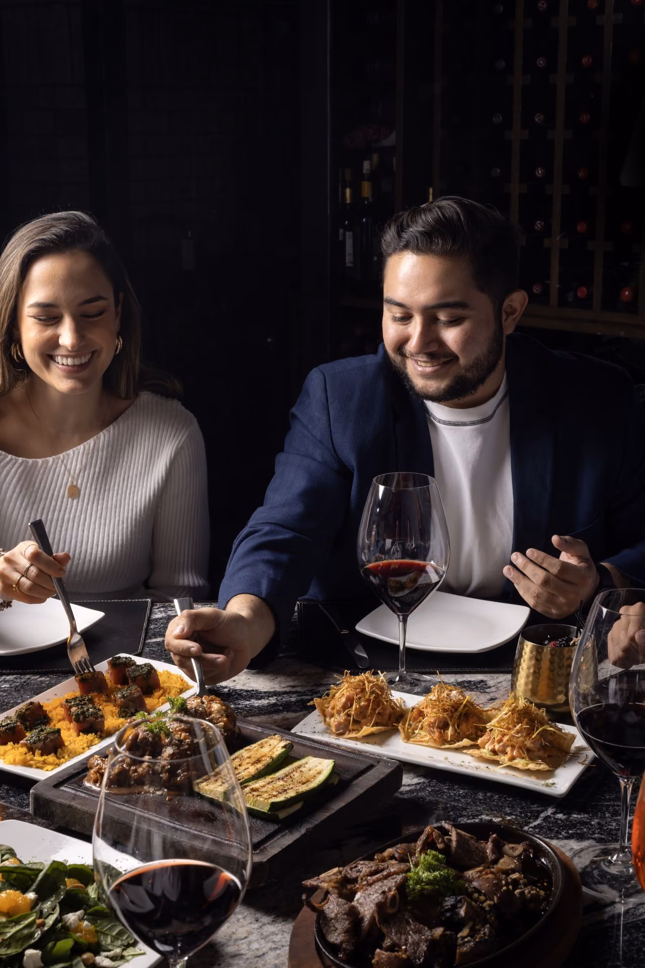 Pareja compartiendo platillos y vino tinto