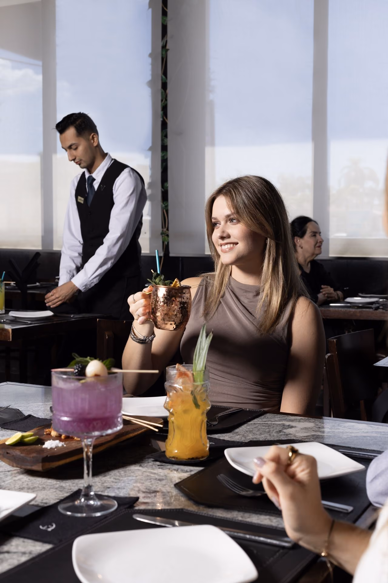 Invitada con coctel junto al ventanal