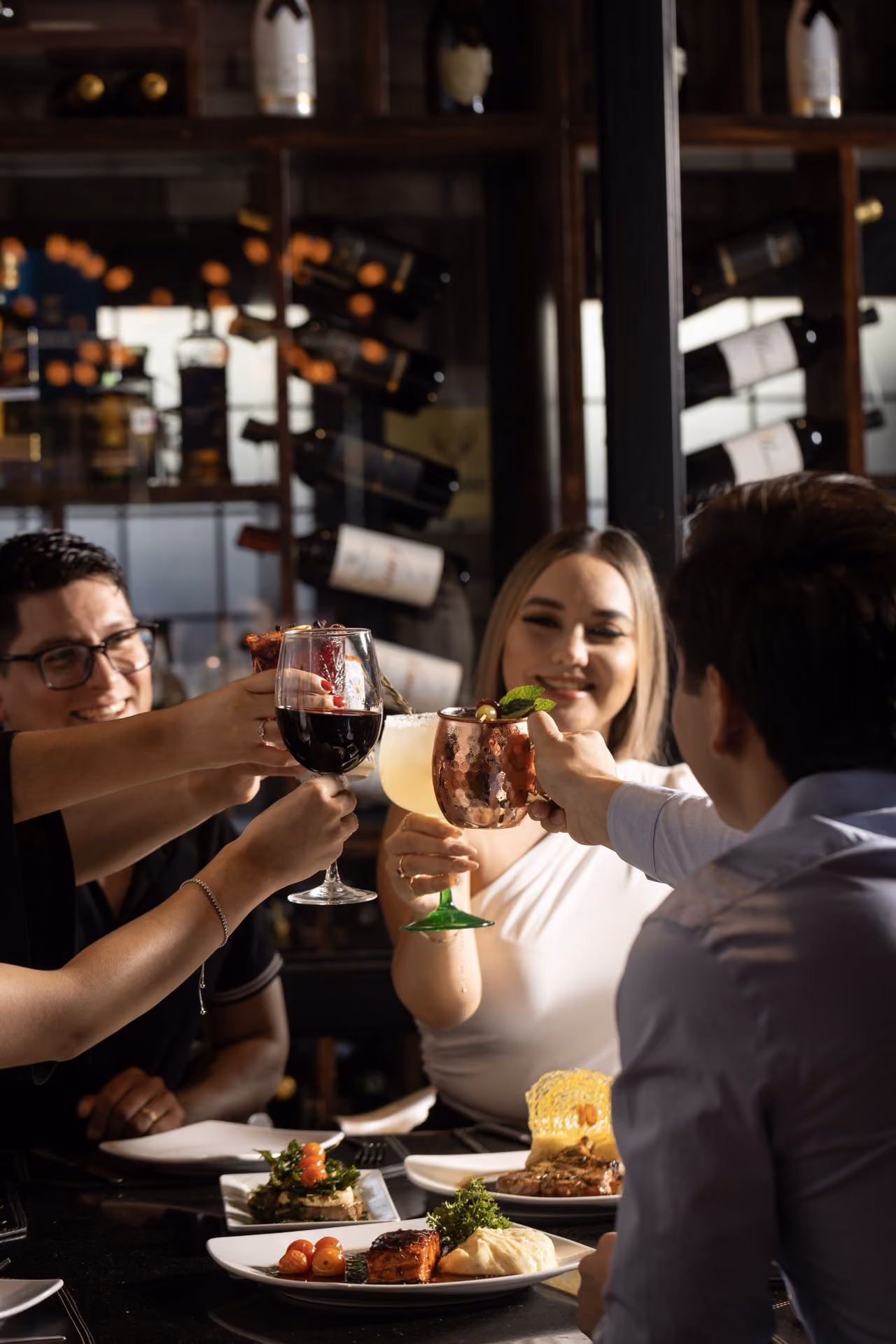 Amigos brindando frente a la cava de vinos