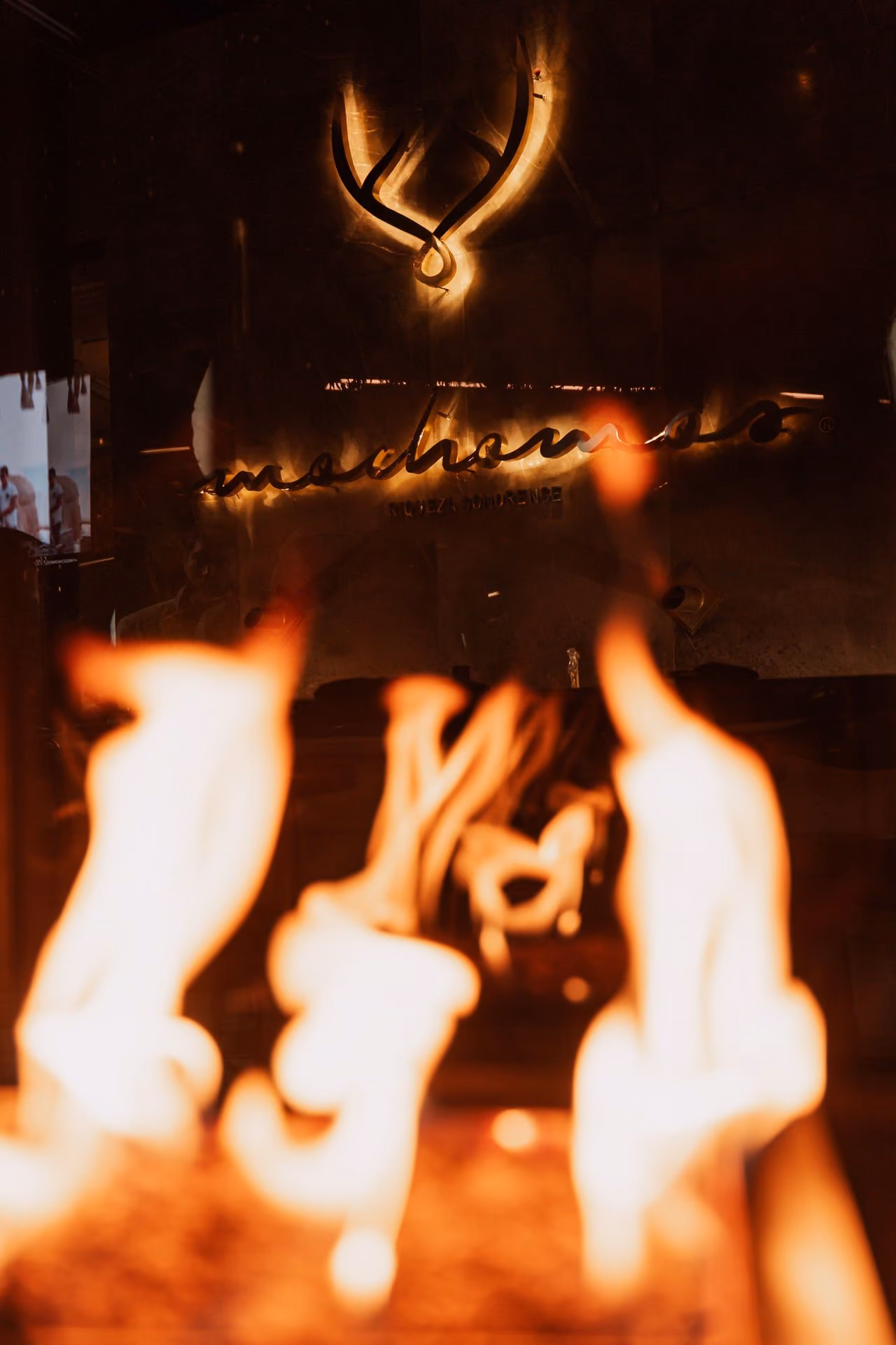 Fuego de la chimenea frente al logo iluminado de Mochomos