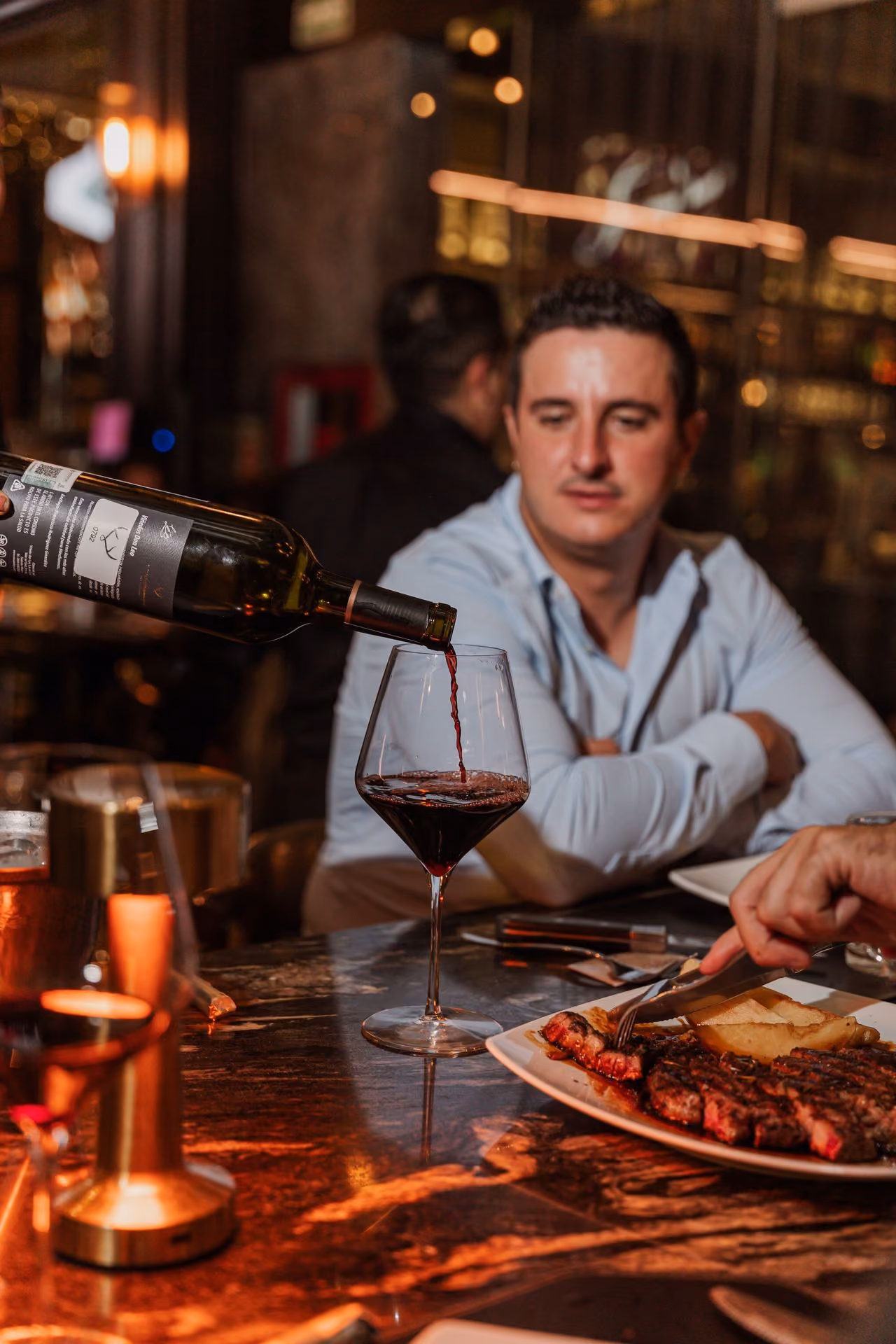 Mesero sirviendo vino tinto a un invitado