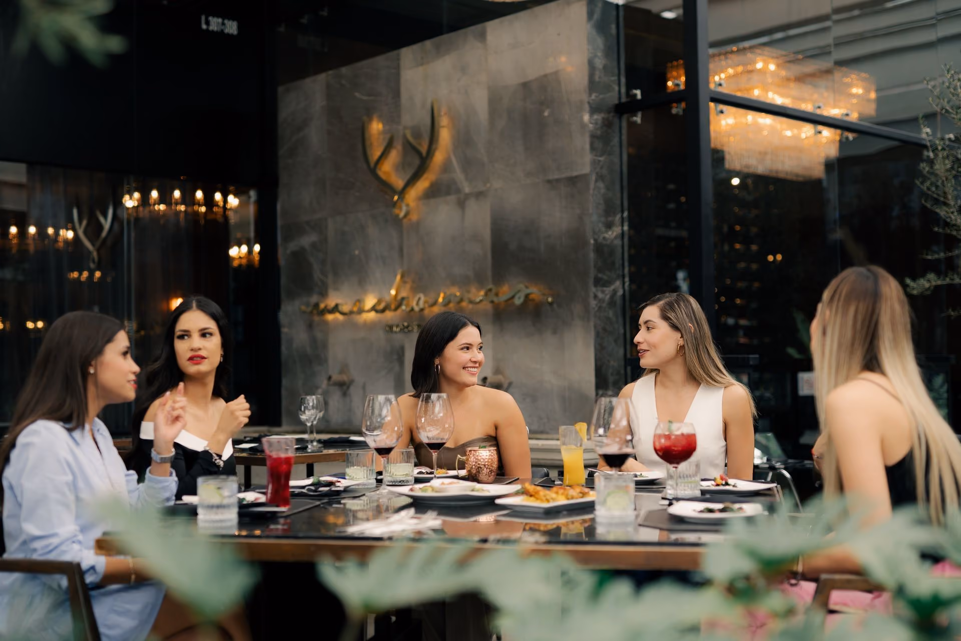 Amigas comiendo en la terraza frente al logo dorado