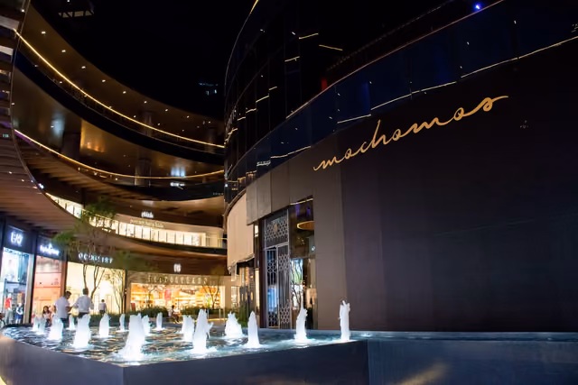 Fachada de Mochomos Guadalajara de noche, con el nombre en dorado y la fuente al frente