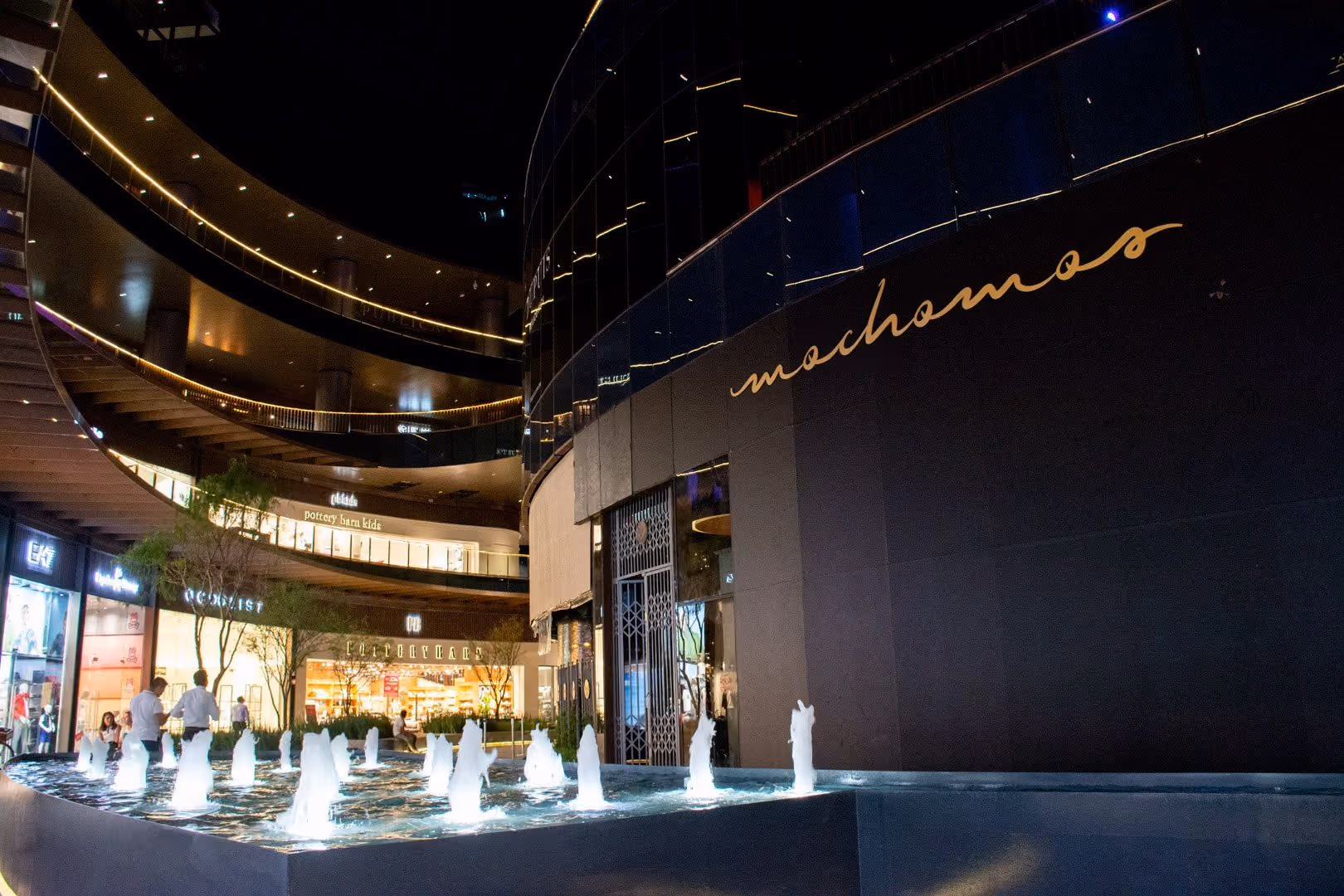 Fachada de Mochomos Guadalajara de noche, con el nombre en dorado y la fuente al frente
