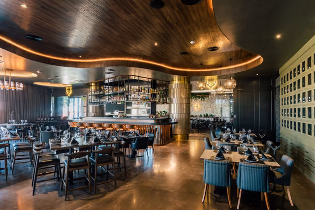 Salón de Mochomos Mérida con techo de madera curvo y barra iluminada