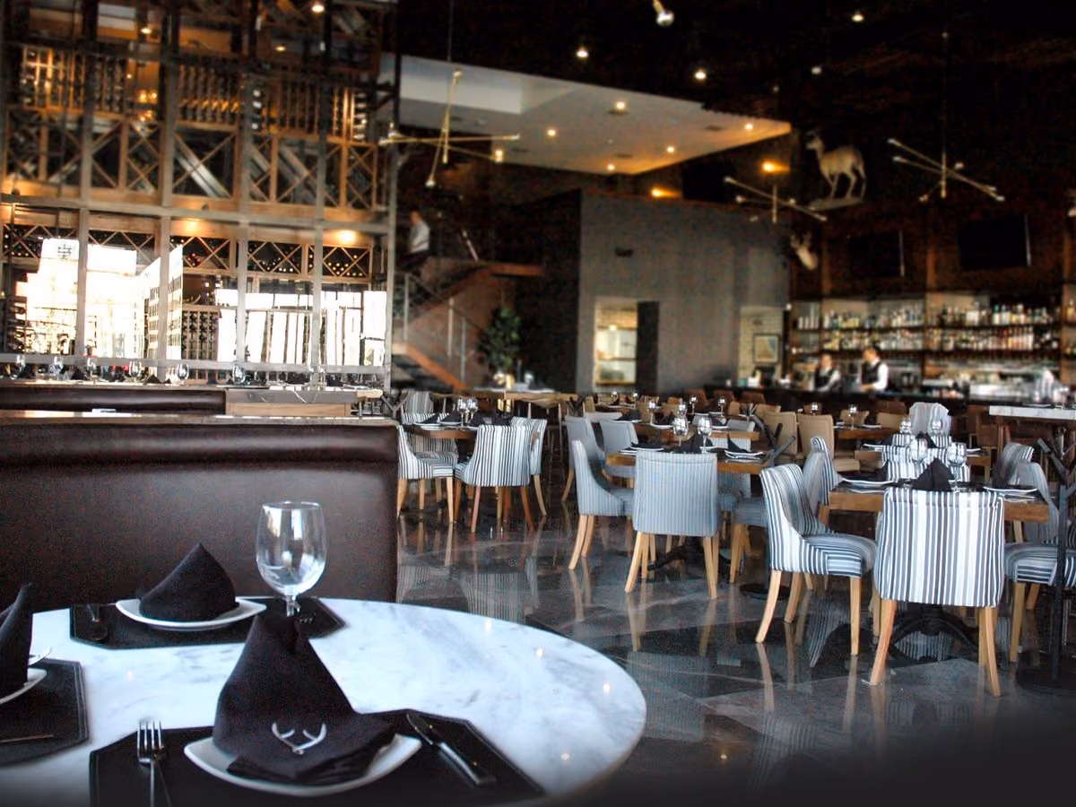 Salón de Mochomos Mexicali con sillas a rayas y la cava al fondo