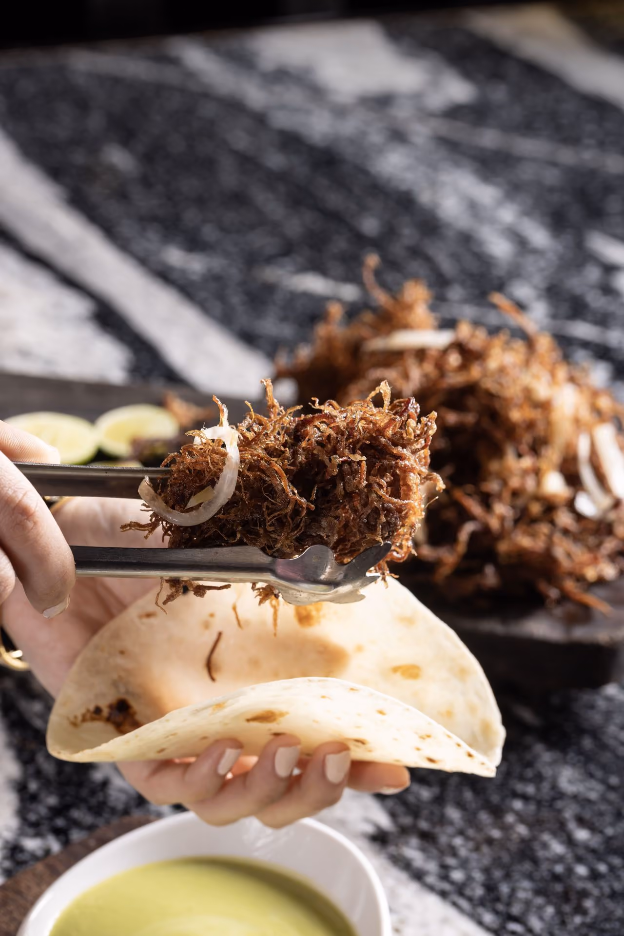 Taco de carne deshebrada armándose en tortilla de harina