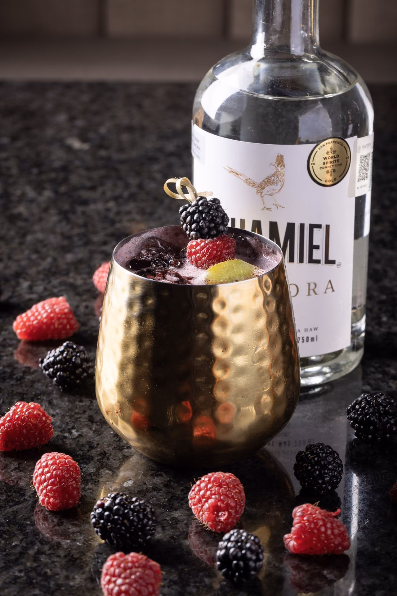 Coctel en vaso dorado con moras y frambuesas