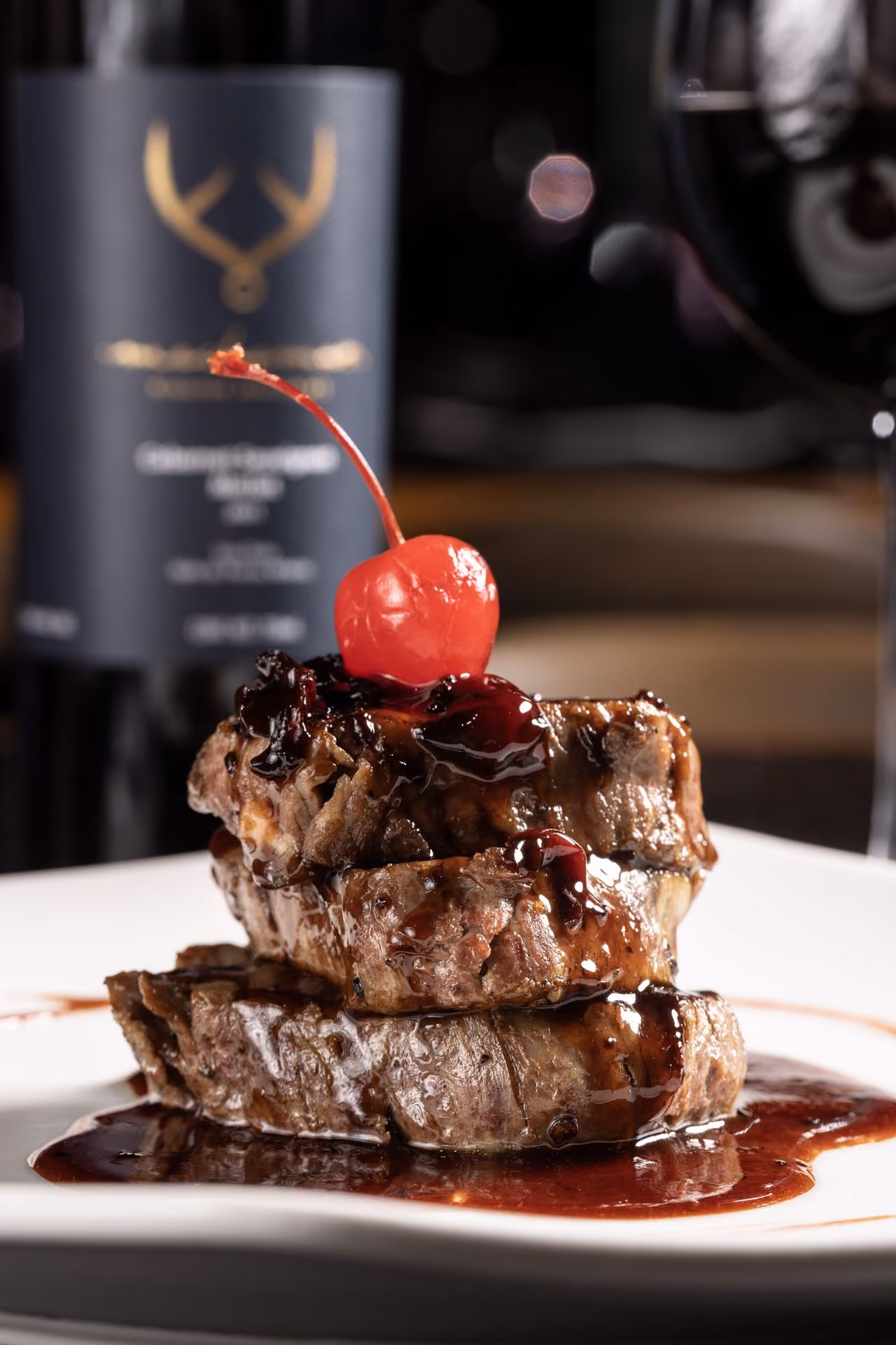 Medallones de filete con cereza y botella de vino de la casa