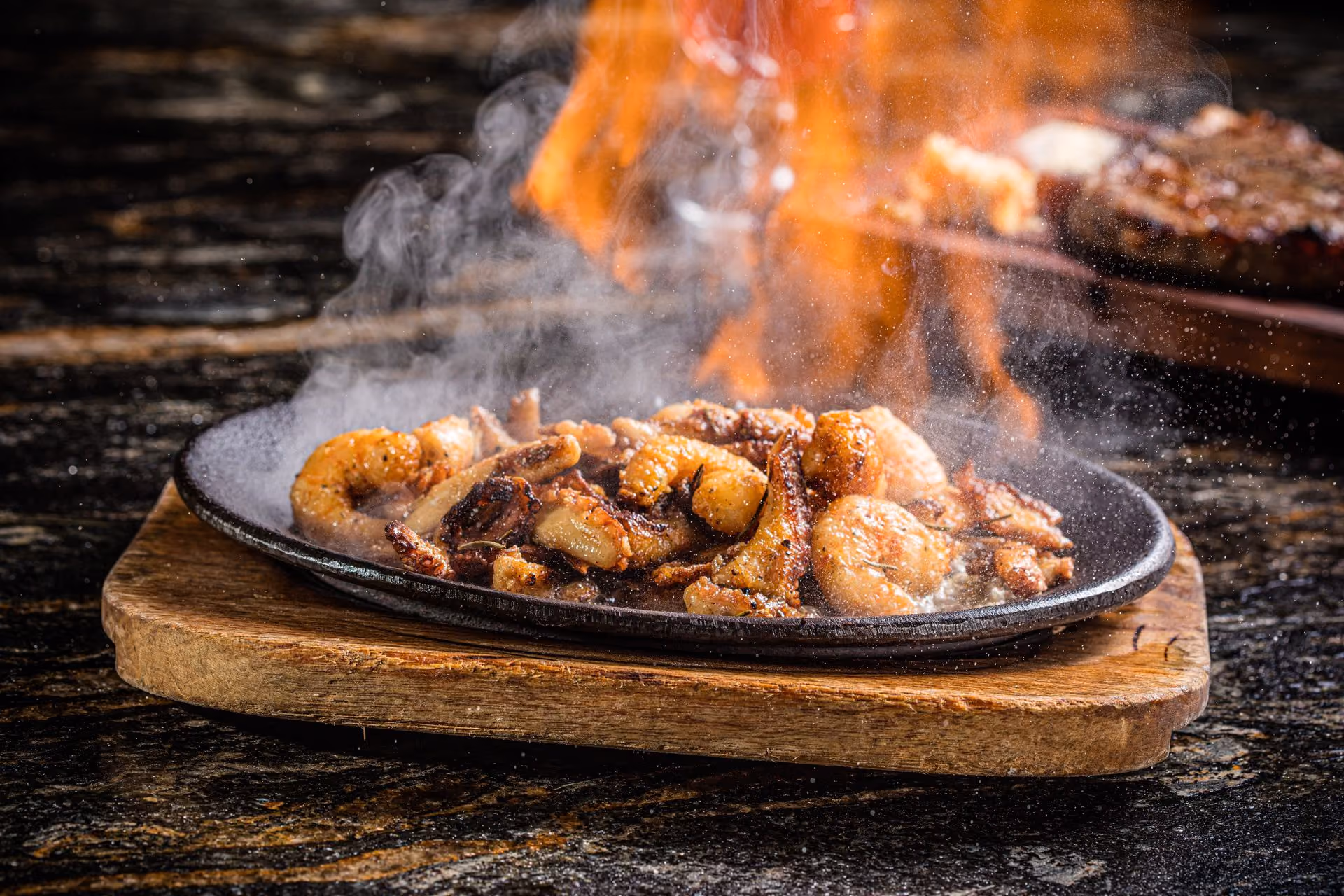 Mariscos flameados sobre plato de hierro