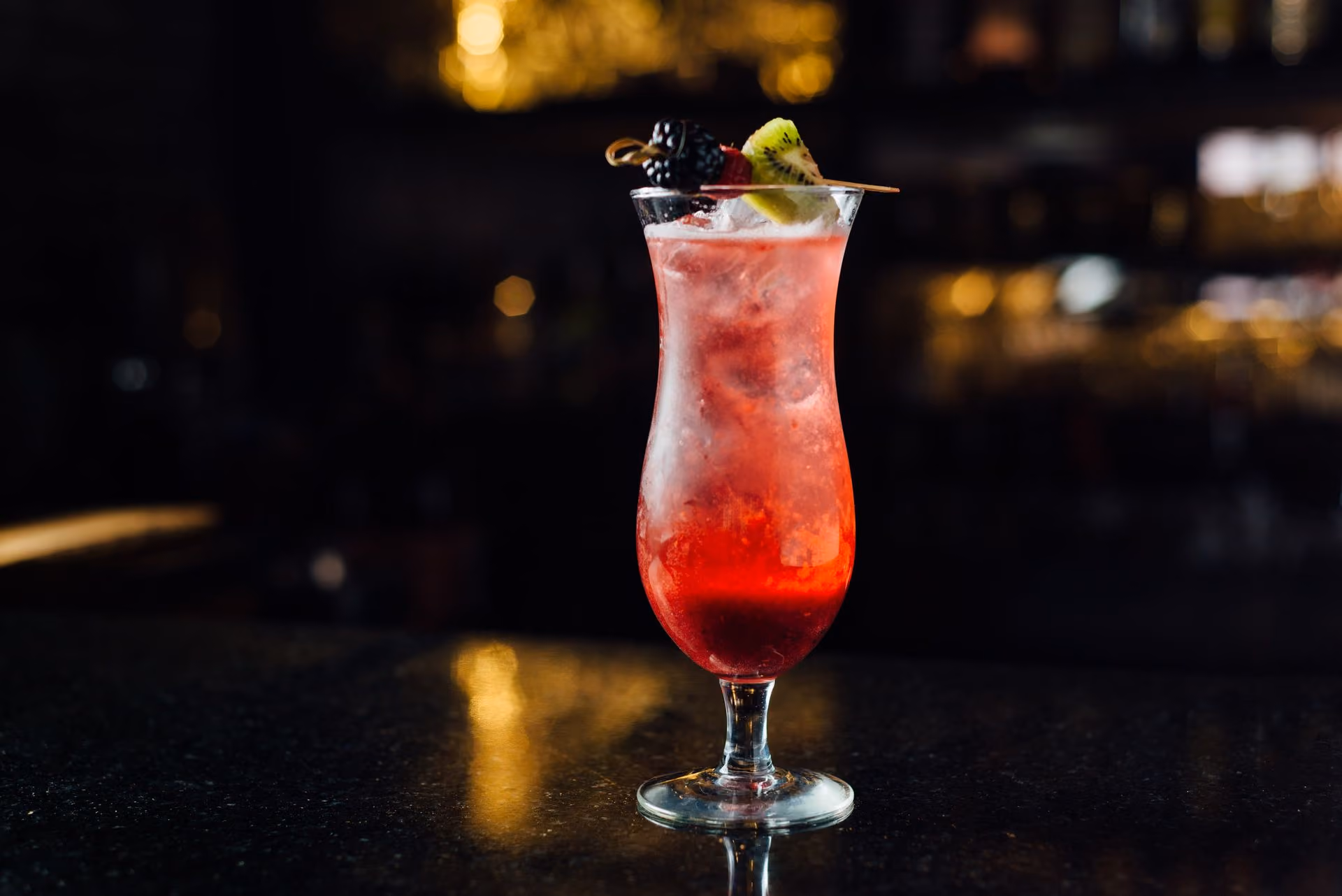Coctel rojo con fruta sobre la barra