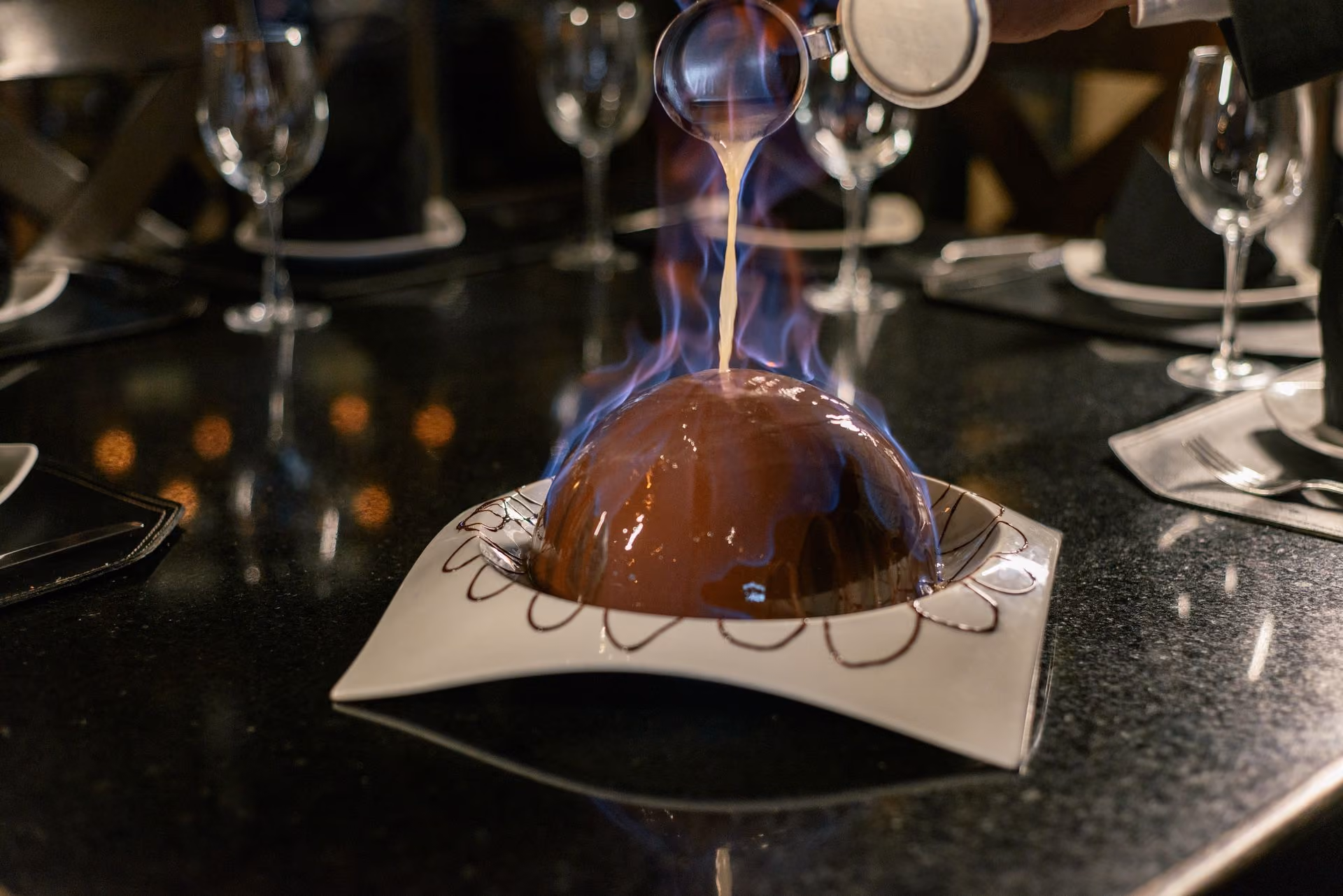 Postre de esfera de chocolate bañado al momento en la mesa
