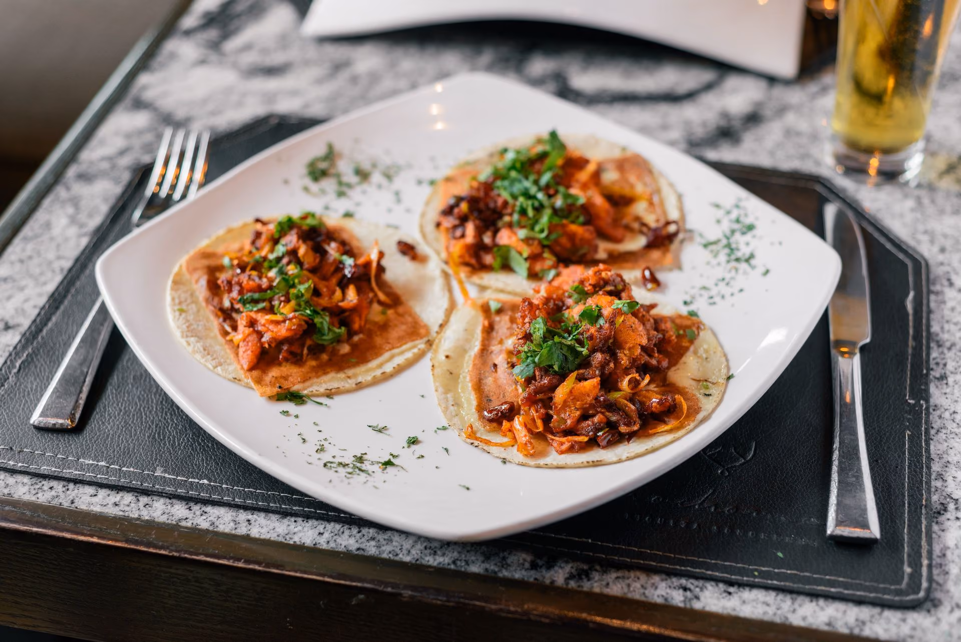 Tres tostadas de carne en plato cuadrado