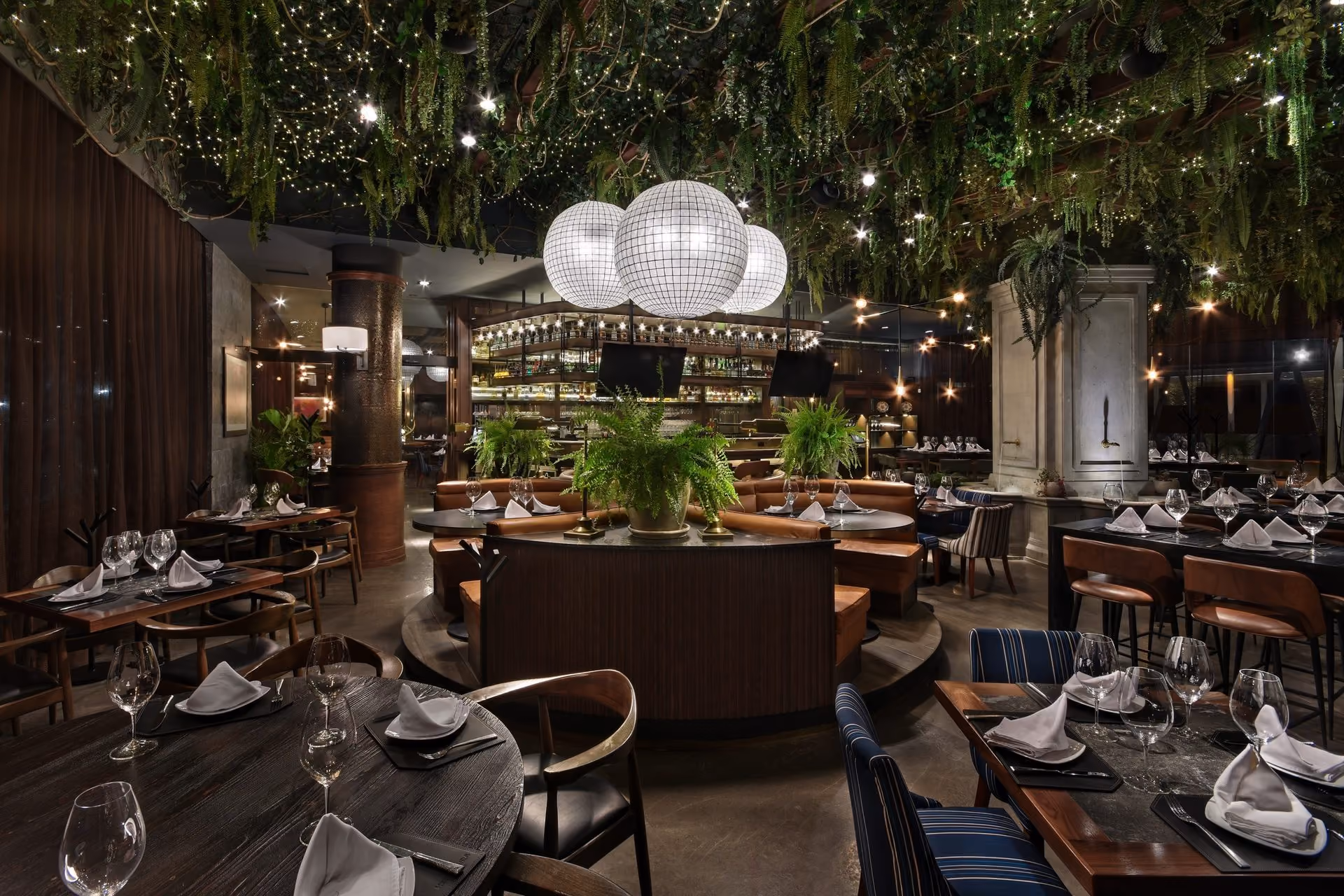 Salón de Mochomos Saltillo de noche, con plantas colgantes y lámparas de globo